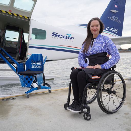 Woman sitting in wheelchair, next to seaplane with a mobility lift